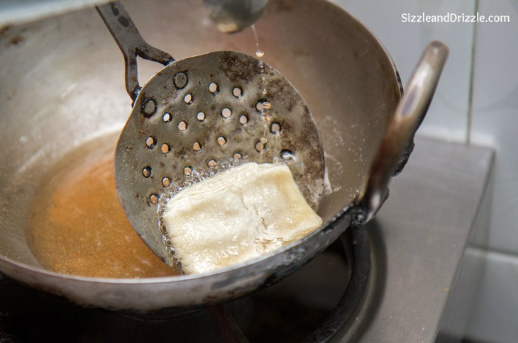 Hold each on eon side of the vessel with a slotted spoon and pour hot ghee on each side